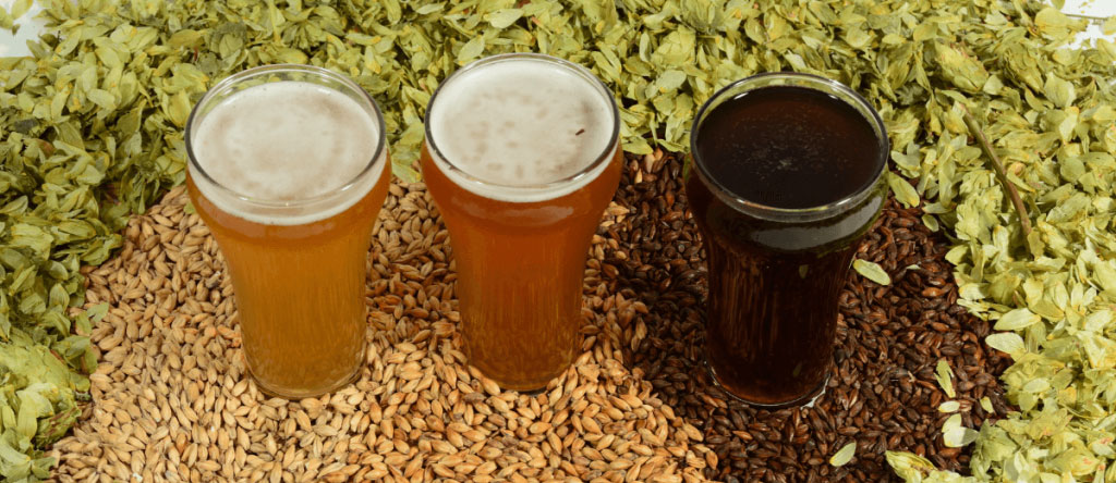 three glasses of different colored beer
